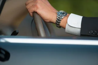 Hands resting calmly on a car steering wheel